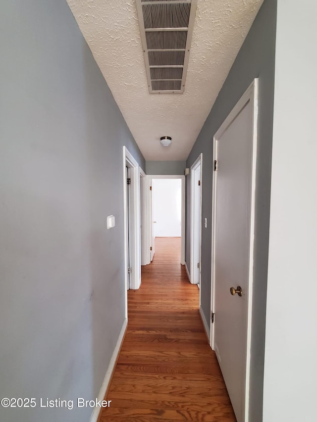 corridor featuring wood-type flooring and a textured ceiling