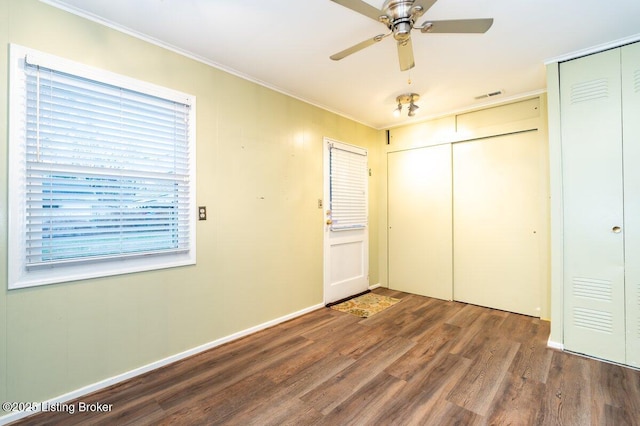 unfurnished bedroom featuring dark hardwood / wood-style flooring, two closets, ceiling fan, and ornamental molding