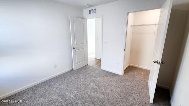 unfurnished bedroom featuring a walk in closet, light carpet, and a closet