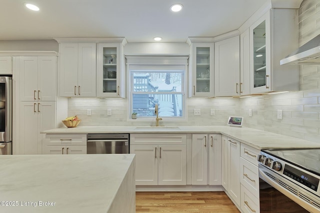 kitchen with white cabinets, sink, decorative backsplash, wall chimney exhaust hood, and stainless steel appliances