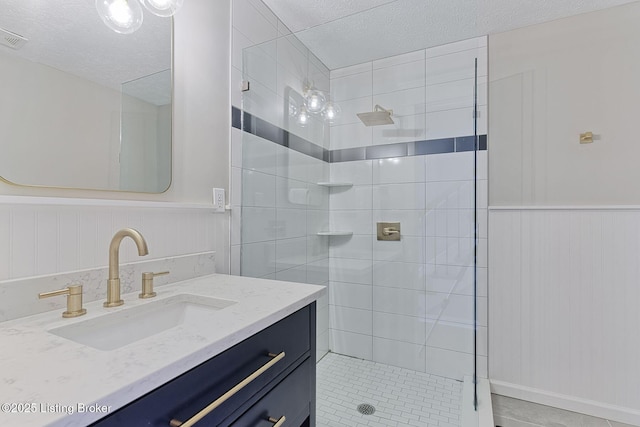 bathroom with a tile shower, tile patterned floors, vanity, and a textured ceiling