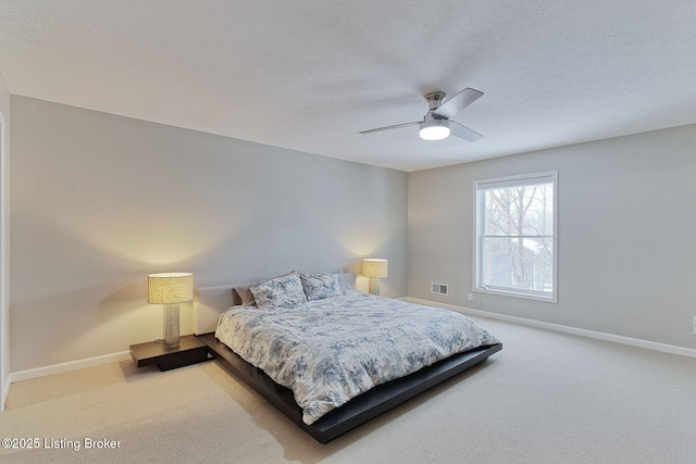 bedroom featuring light carpet, a textured ceiling, and ceiling fan