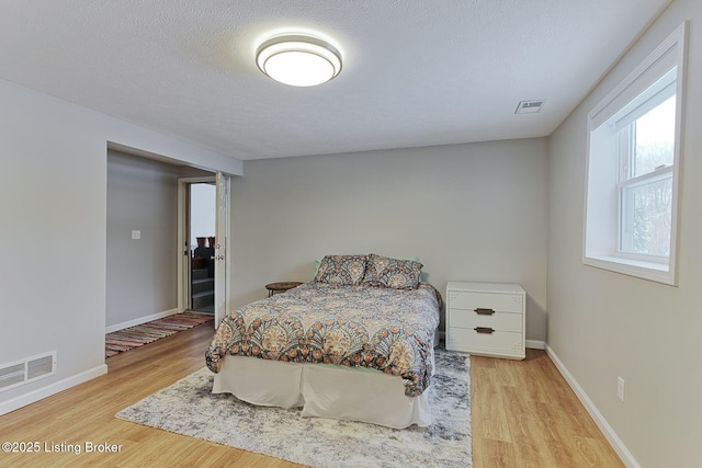 bedroom with a textured ceiling and light hardwood / wood-style floors