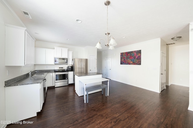 kitchen featuring a center island, white cabinetry, a chandelier, pendant lighting, and appliances with stainless steel finishes