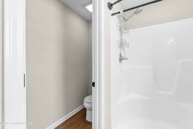 bathroom with walk in shower, hardwood / wood-style floors, and toilet