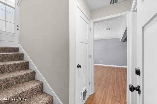 stairway with a textured ceiling and hardwood / wood-style flooring