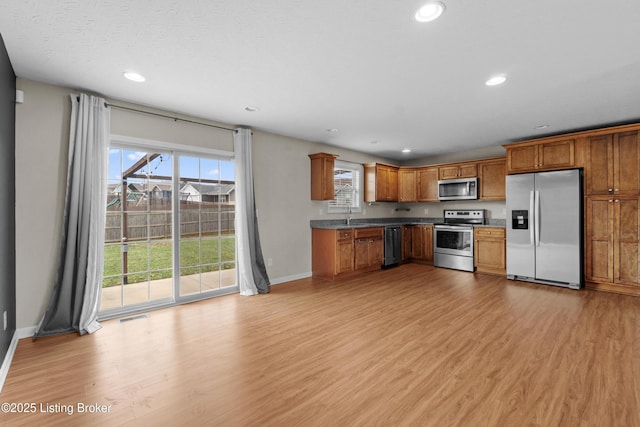 kitchen featuring recessed lighting, appliances with stainless steel finishes, brown cabinetry, and light wood-type flooring