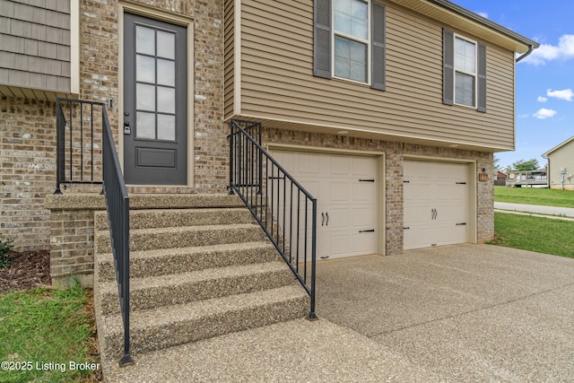 view of exterior entry featuring driveway, a garage, and brick siding