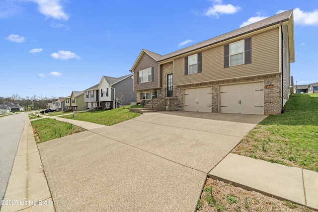 bi-level home featuring driveway, an attached garage, a front yard, and a residential view