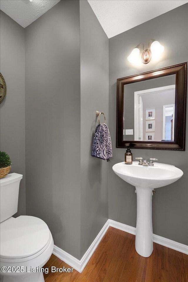 bathroom with hardwood / wood-style flooring, a textured ceiling, and toilet