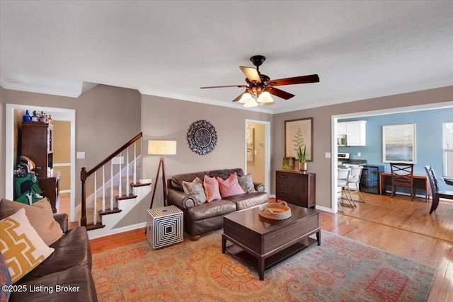 living room featuring crown molding, ceiling fan, and light wood-type flooring