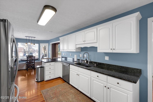 kitchen featuring white cabinetry, hanging light fixtures, sink, and appliances with stainless steel finishes