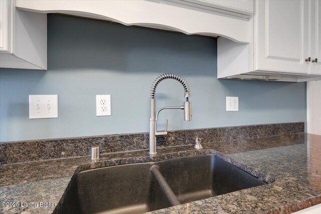 kitchen featuring sink, dark stone counters, and white cabinets