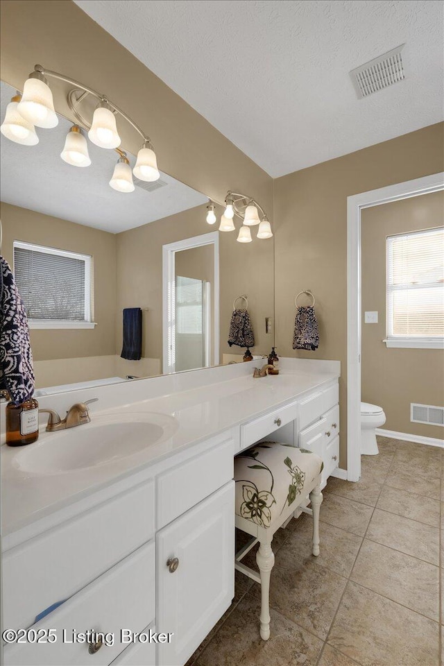 bathroom with tile patterned flooring, vanity, a textured ceiling, and toilet