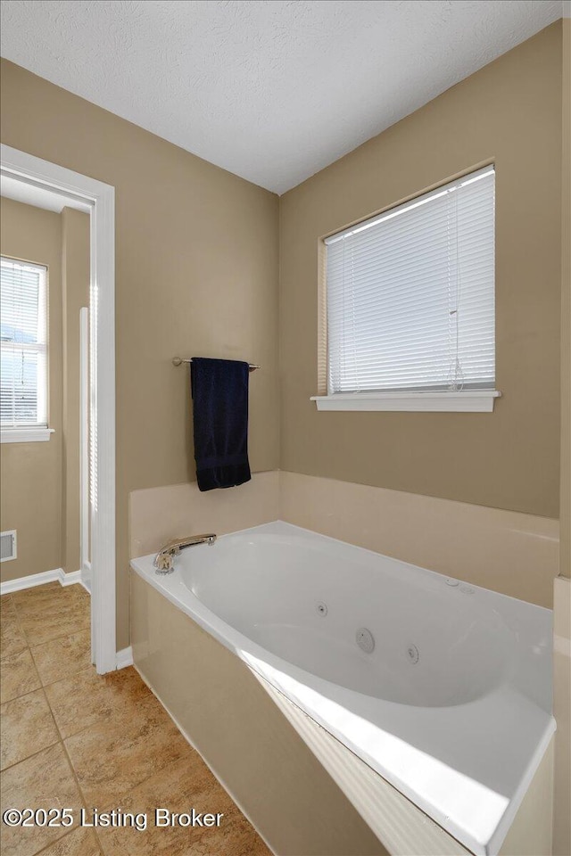 bathroom featuring tile patterned flooring, a textured ceiling, and a tub