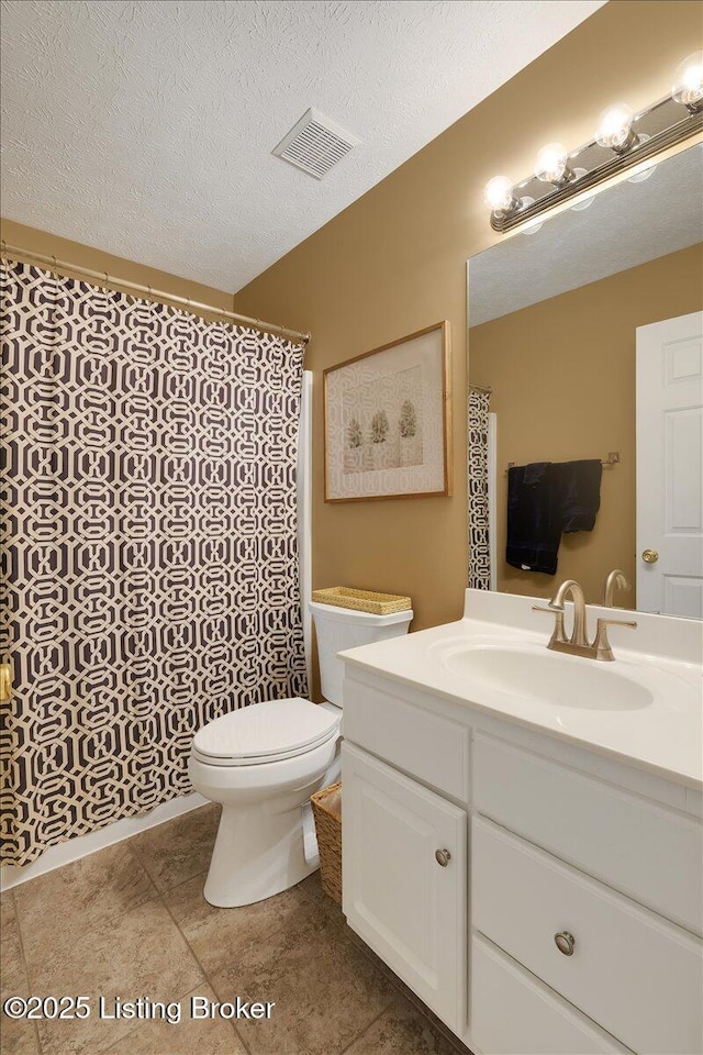 bathroom with vanity, toilet, tile patterned flooring, and a textured ceiling