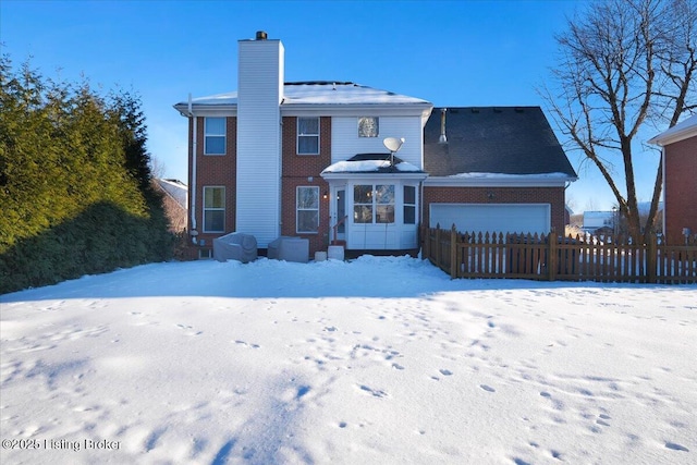 snow covered house featuring a garage