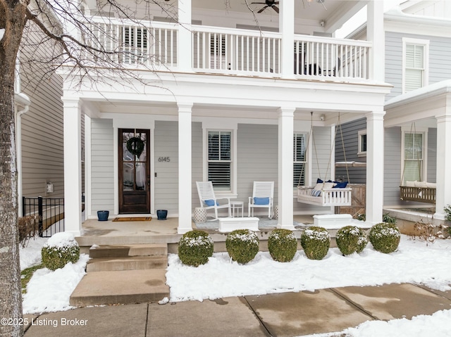 snow covered property entrance featuring a balcony and a porch