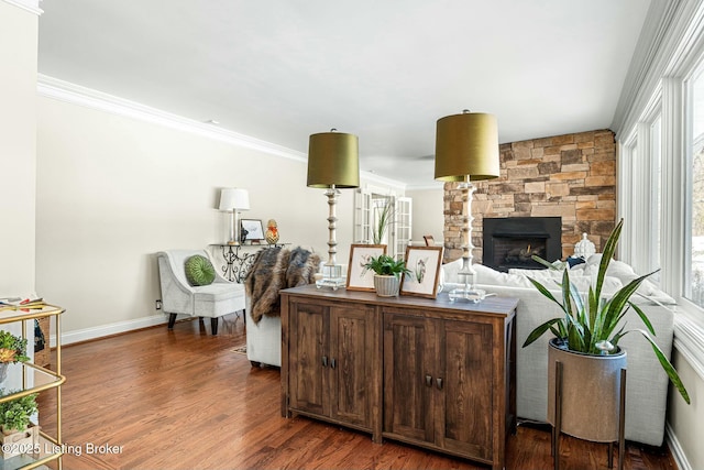 living room with dark hardwood / wood-style floors, crown molding, and a stone fireplace