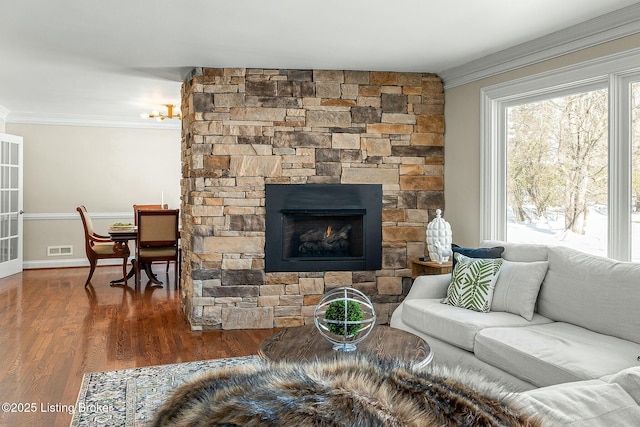 living room featuring dark hardwood / wood-style flooring, crown molding, and a stone fireplace