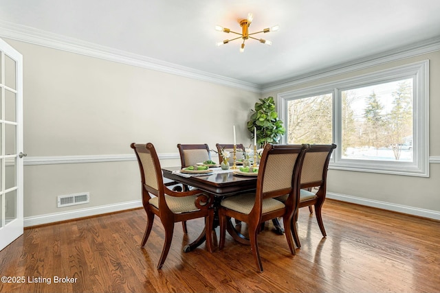 dining room with a healthy amount of sunlight, hardwood / wood-style floors, and crown molding