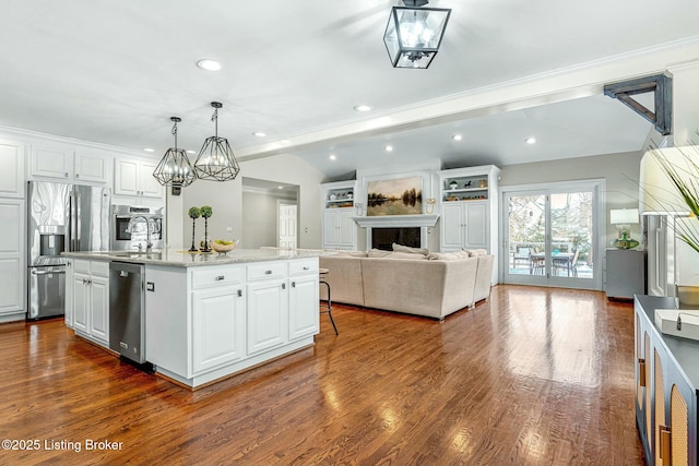 kitchen with white cabinets, stainless steel appliances, a kitchen island with sink, and pendant lighting