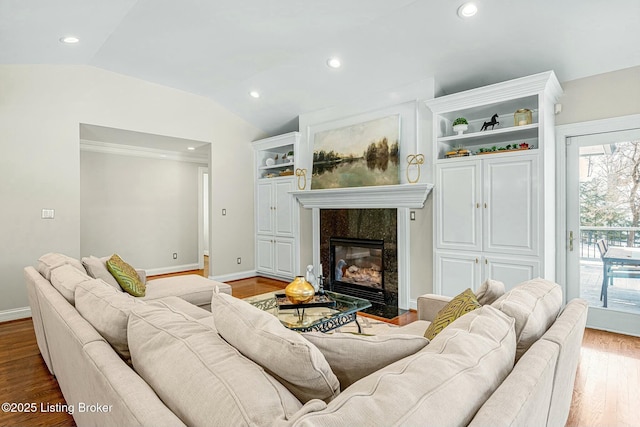 living room with hardwood / wood-style floors, vaulted ceiling, and a high end fireplace