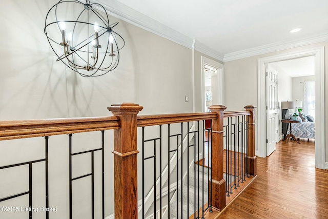 hall with hardwood / wood-style flooring, an inviting chandelier, and crown molding