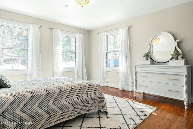 bedroom with dark hardwood / wood-style flooring and multiple windows