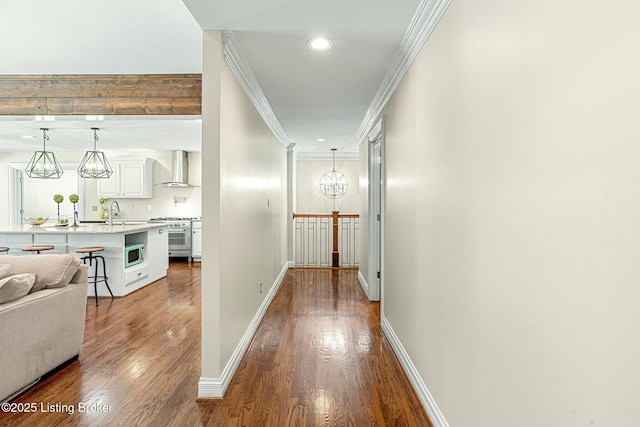 corridor with a notable chandelier, ornamental molding, and hardwood / wood-style floors