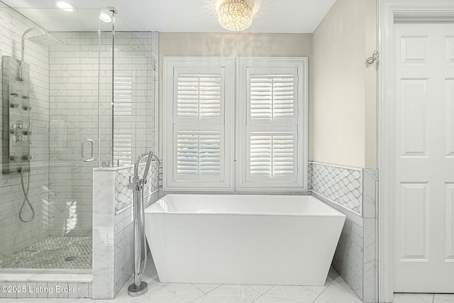 bathroom featuring tile walls, a notable chandelier, and separate shower and tub