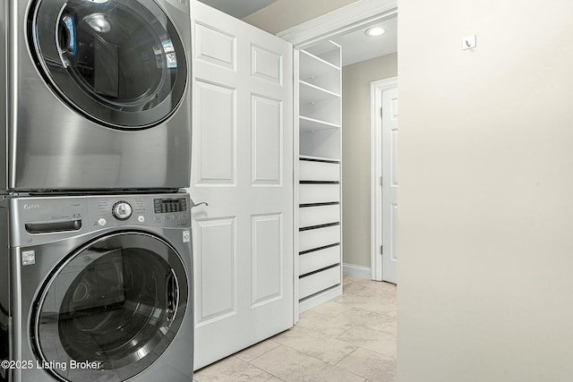 laundry area featuring stacked washer / drying machine and light tile patterned floors