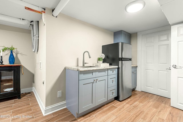 kitchen featuring sink, stainless steel refrigerator, and gray cabinets