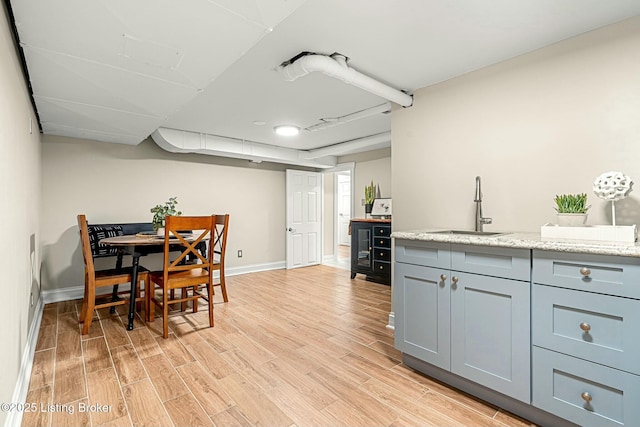 kitchen featuring light stone counters, sink, and light wood-type flooring