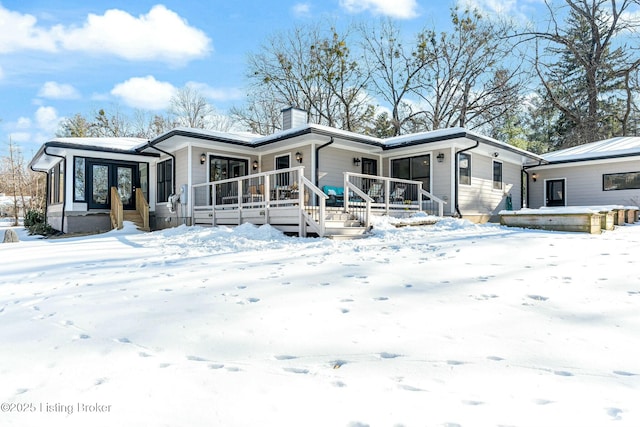 snow covered back of property with a porch and french doors