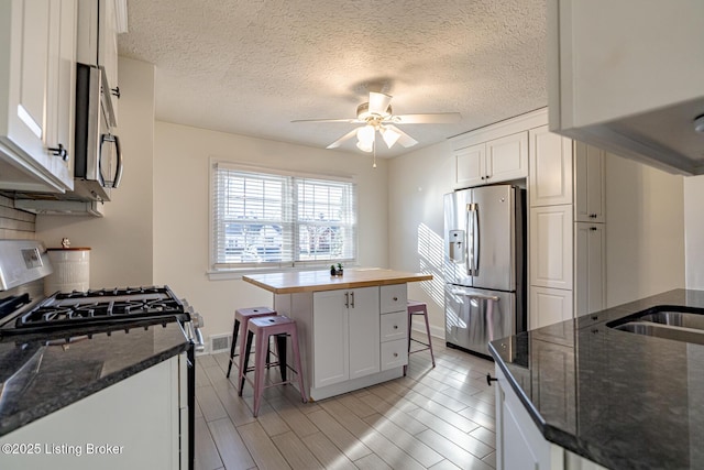 kitchen featuring white cabinetry, a center island, a breakfast bar, and appliances with stainless steel finishes