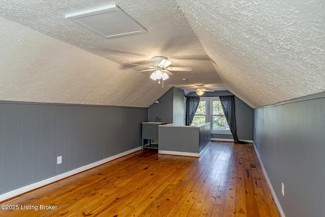 bonus room with lofted ceiling, hardwood / wood-style floors, and a textured ceiling