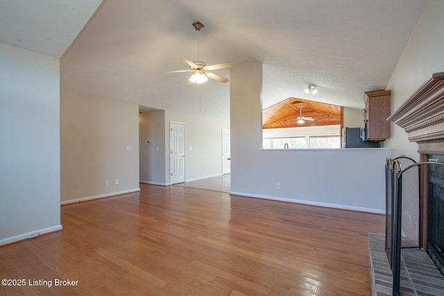 unfurnished living room with a brick fireplace, hardwood / wood-style flooring, lofted ceiling, and ceiling fan