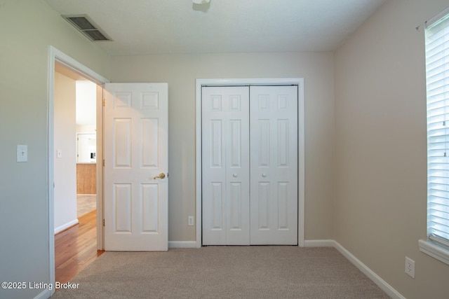 unfurnished bedroom featuring light colored carpet and a closet