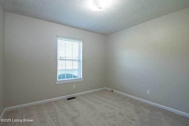 unfurnished room with a textured ceiling and light colored carpet