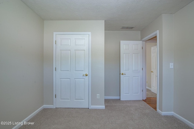 unfurnished bedroom featuring light colored carpet, a closet, and a textured ceiling