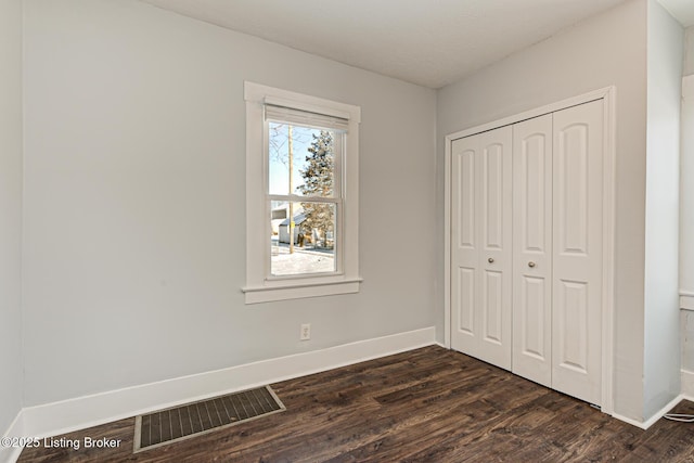 unfurnished bedroom with dark wood-type flooring and a closet