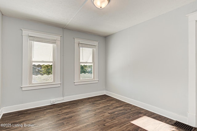 empty room featuring dark hardwood / wood-style flooring and a textured ceiling