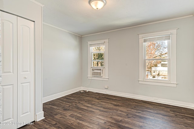 spare room featuring dark wood-type flooring, a wealth of natural light, and crown molding