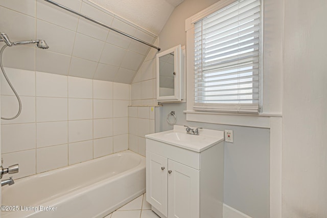 bathroom featuring tile patterned floors, vanity, tiled shower / bath, and vaulted ceiling