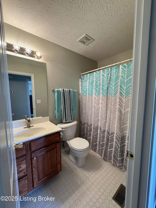 bathroom featuring vanity, toilet, a textured ceiling, and walk in shower