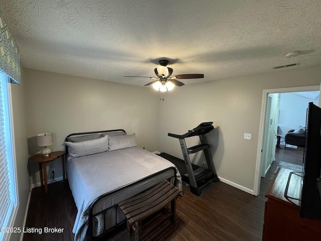 bedroom featuring dark hardwood / wood-style floors, ceiling fan, and a textured ceiling