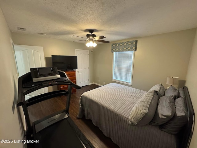 bedroom with a textured ceiling, ceiling fan, and dark wood-type flooring