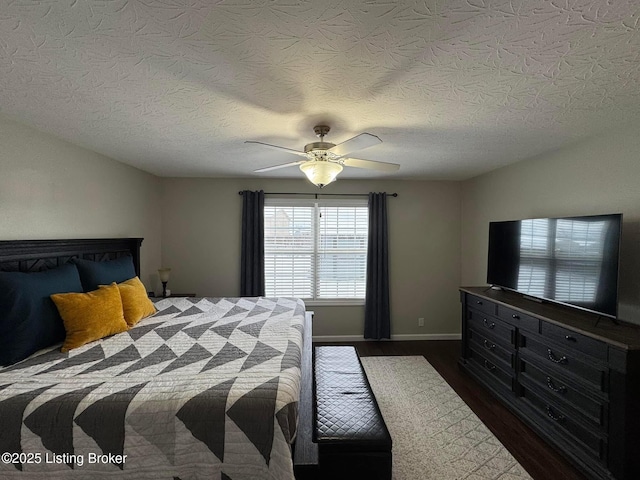 bedroom with ceiling fan, dark hardwood / wood-style flooring, and a textured ceiling