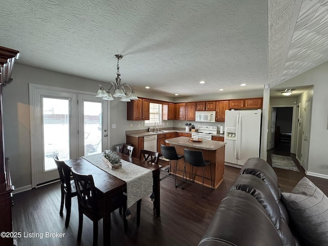 dining space with sink, dark wood-type flooring, a textured ceiling, and a notable chandelier